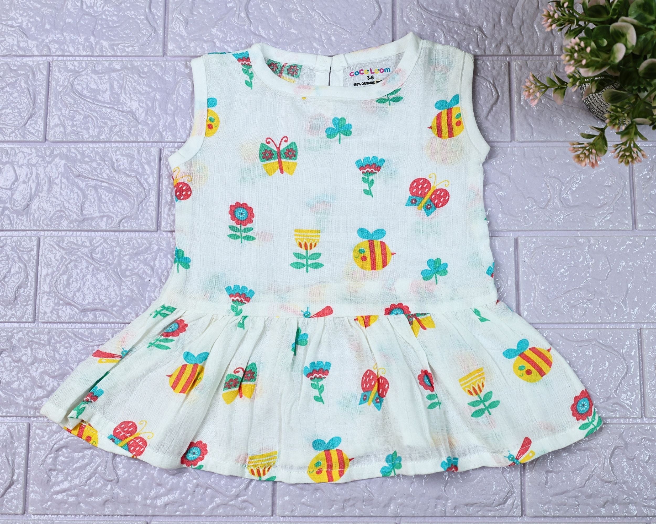 Garden Flutters Baby sleeveless frock in white with button printed with colourful flowers, butterflies and dragonflies themed pattern