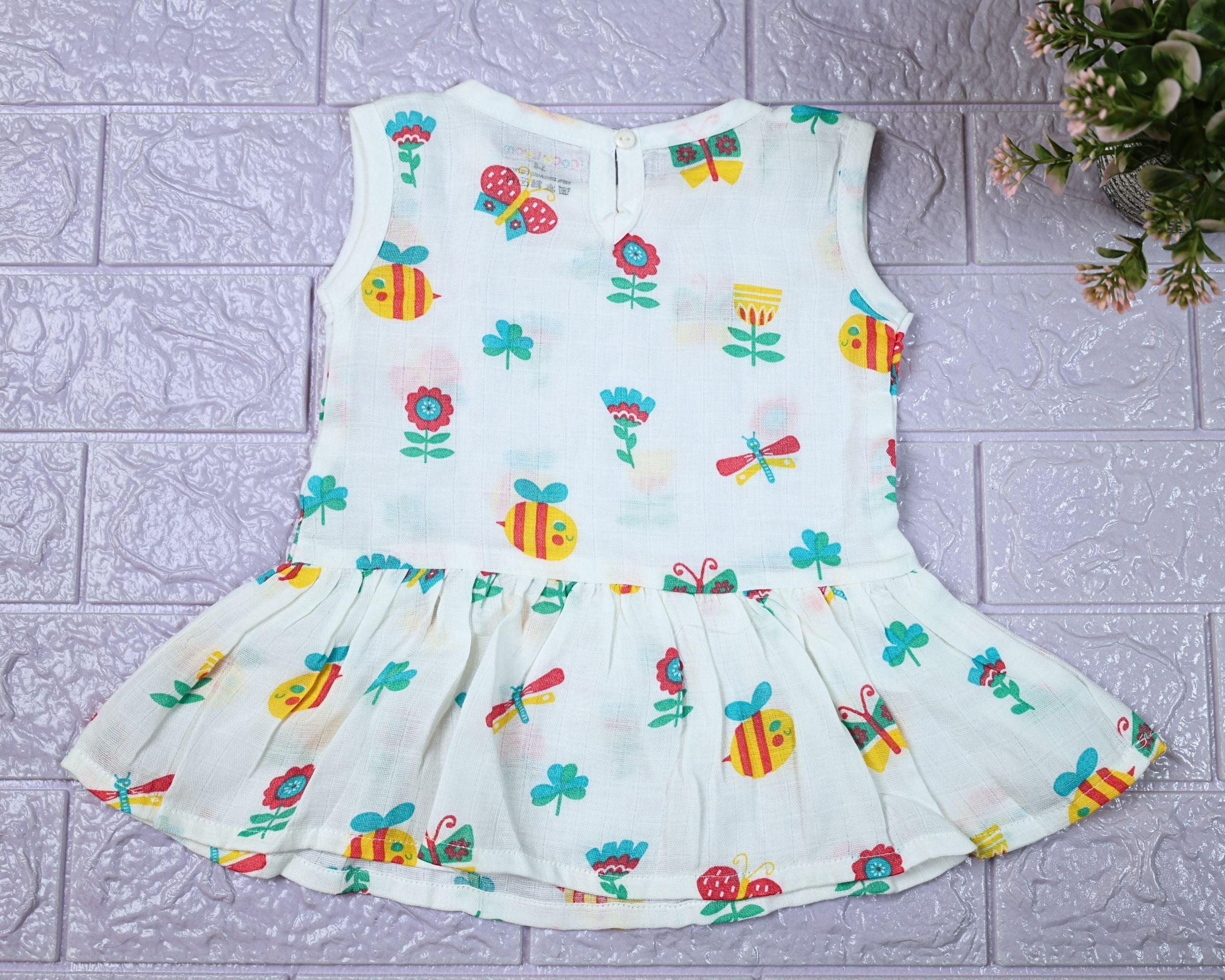 Garden Flutters Baby sleeveless frock in white with button printed with colourful flowers, butterflies and dragonflies themed pattern