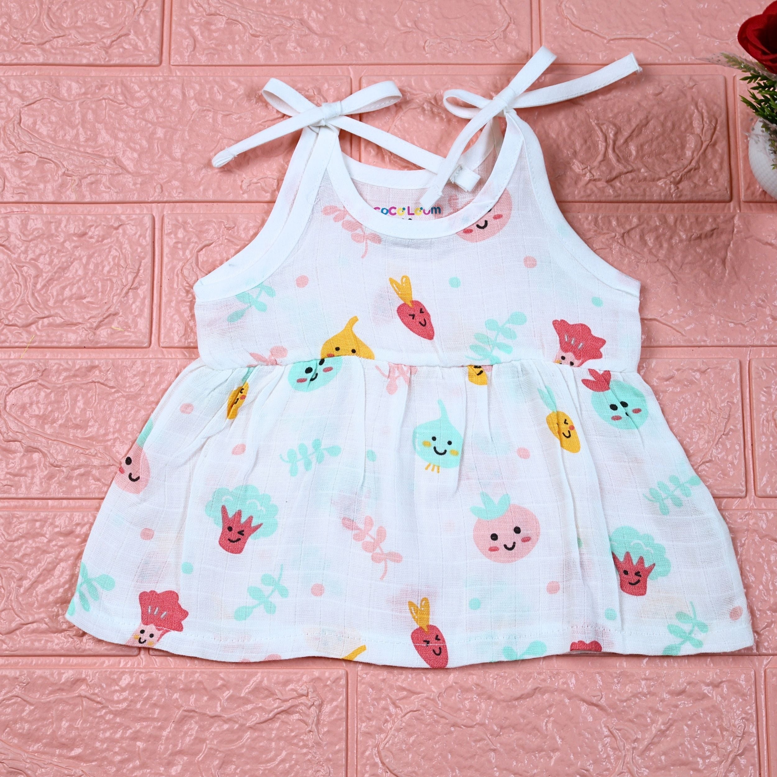Little Veggies baby sleeveless frock in white with tie up shoulders, printed with colourful veggie patterns