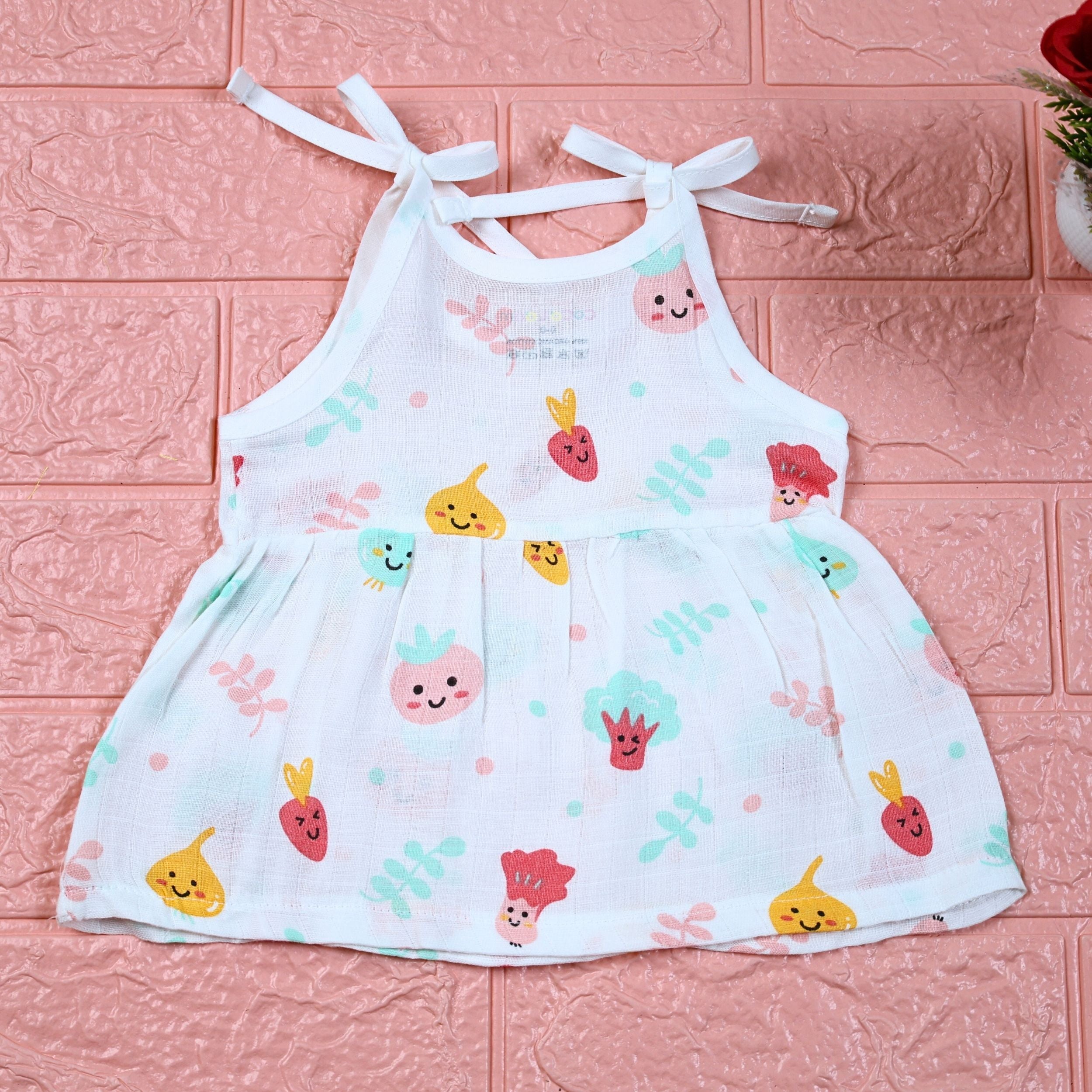Little Veggies baby sleeveless frock in white with tie up shoulders, printed with colourful veggie patterns