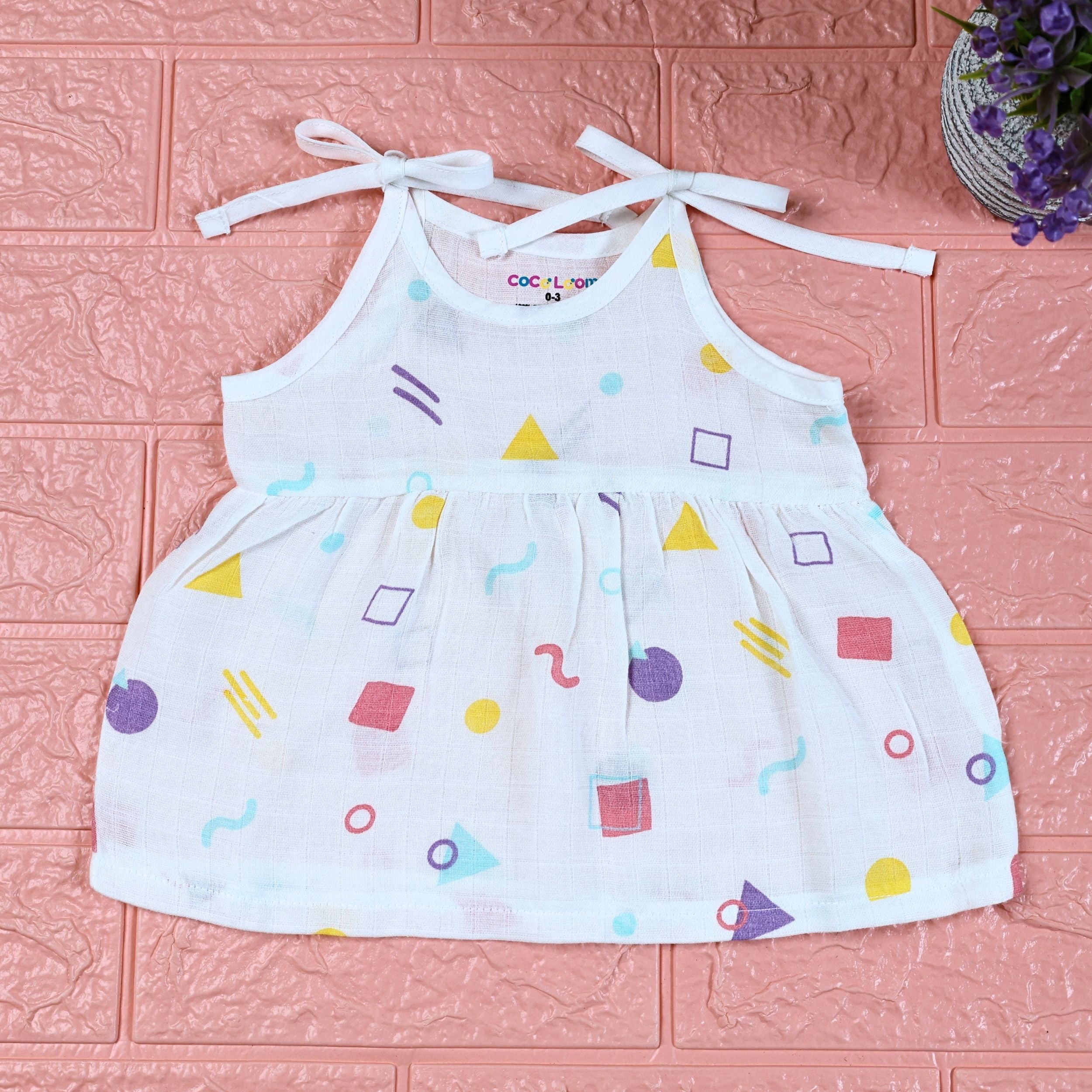 Shape Pops baby frock in white with tie up shoulders printed with colorful geometric pattern