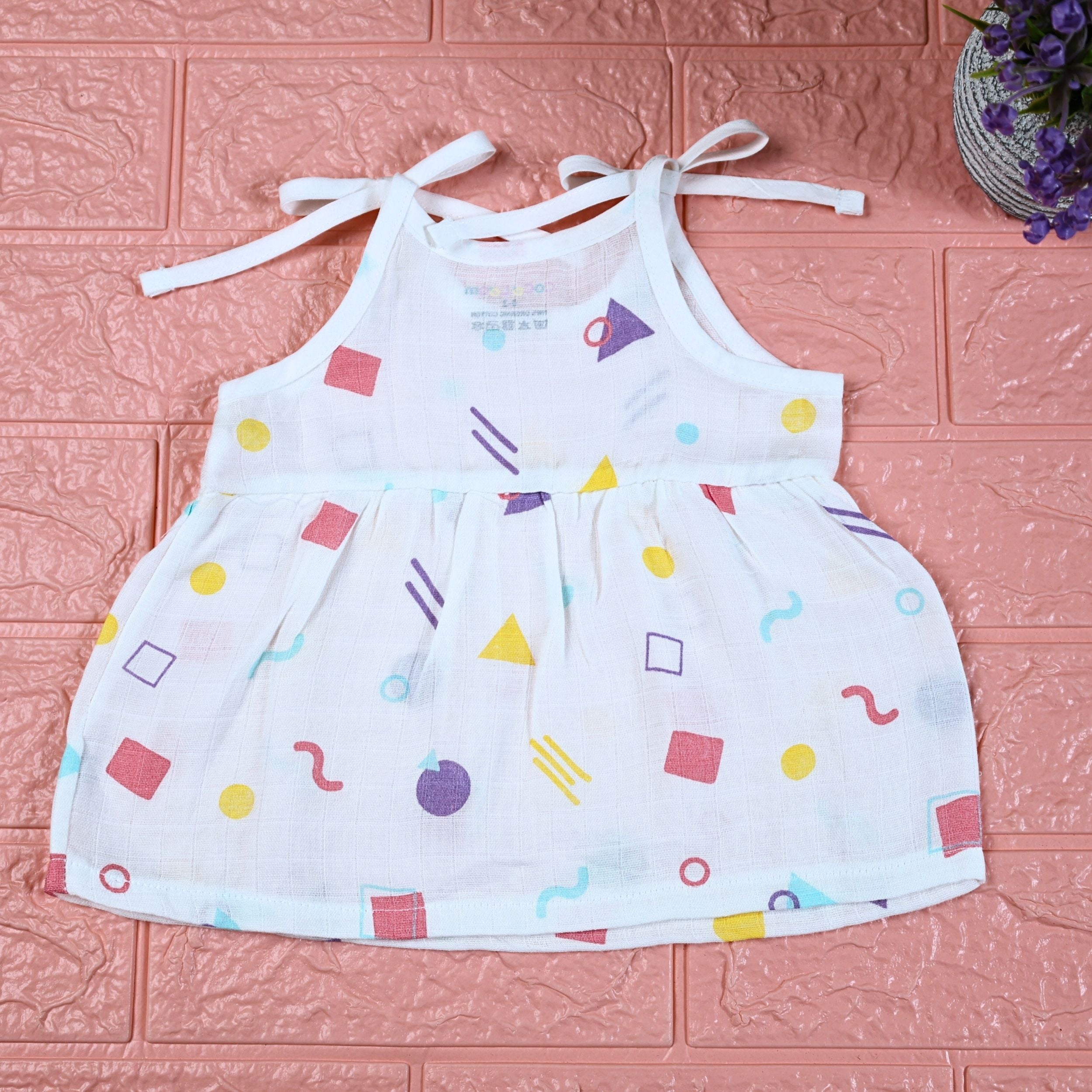 Shape Pops baby frock in white with tie up shoulders printed with colorful geometric pattern