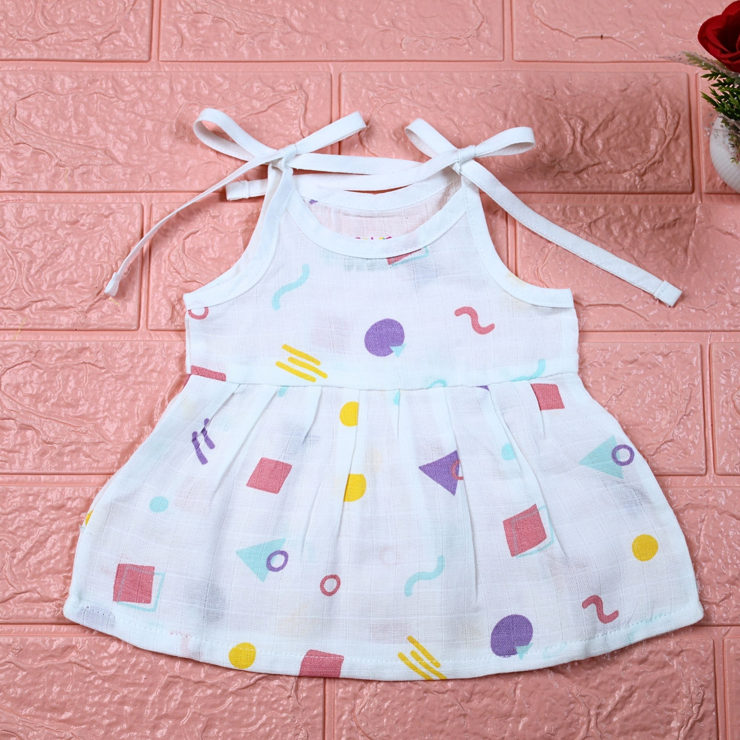 Shape Pops baby frock in white with tie up shoulders printed with colorful geometric pattern