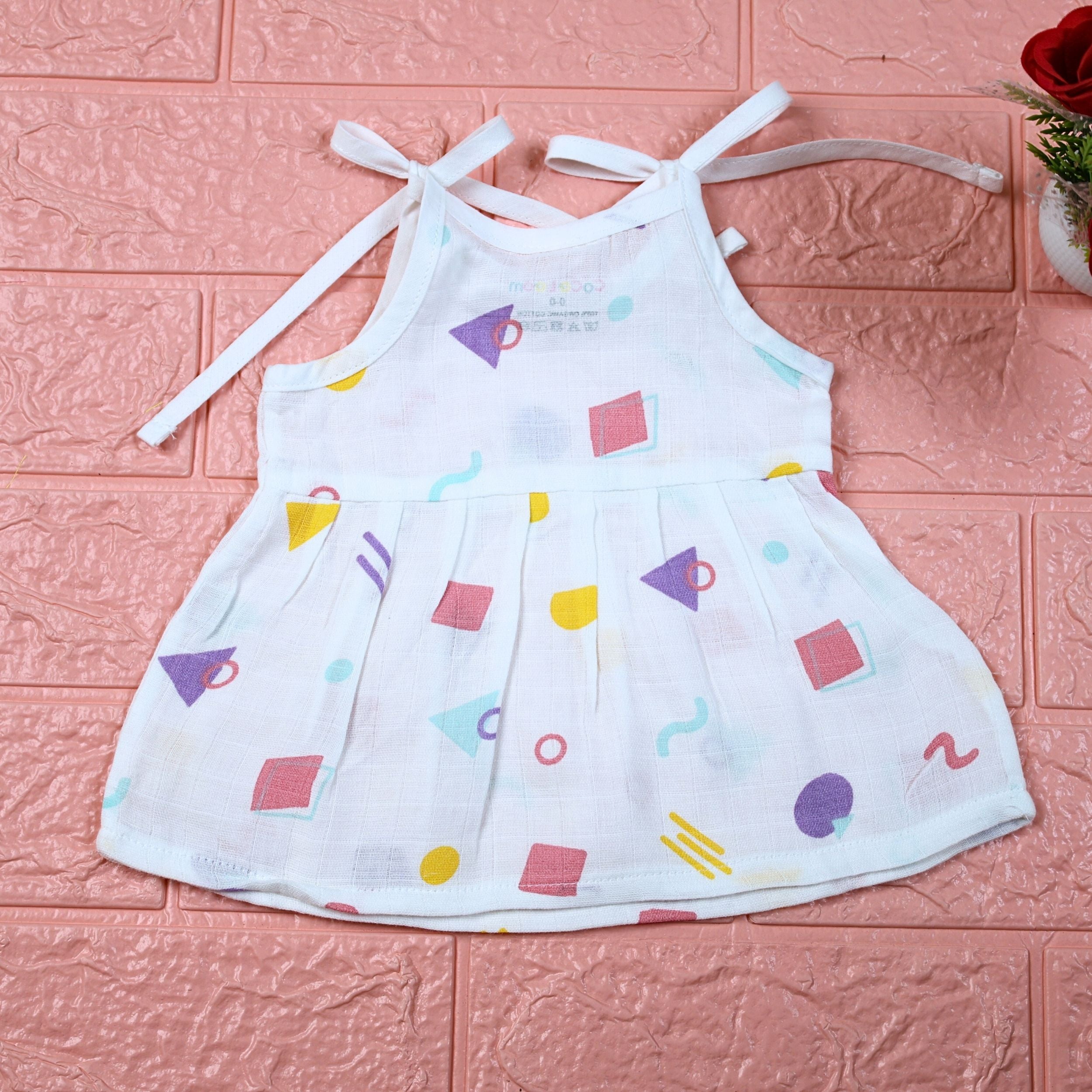 Shape Pops baby frock in white with tie up shoulders printed with colorful geometric pattern
