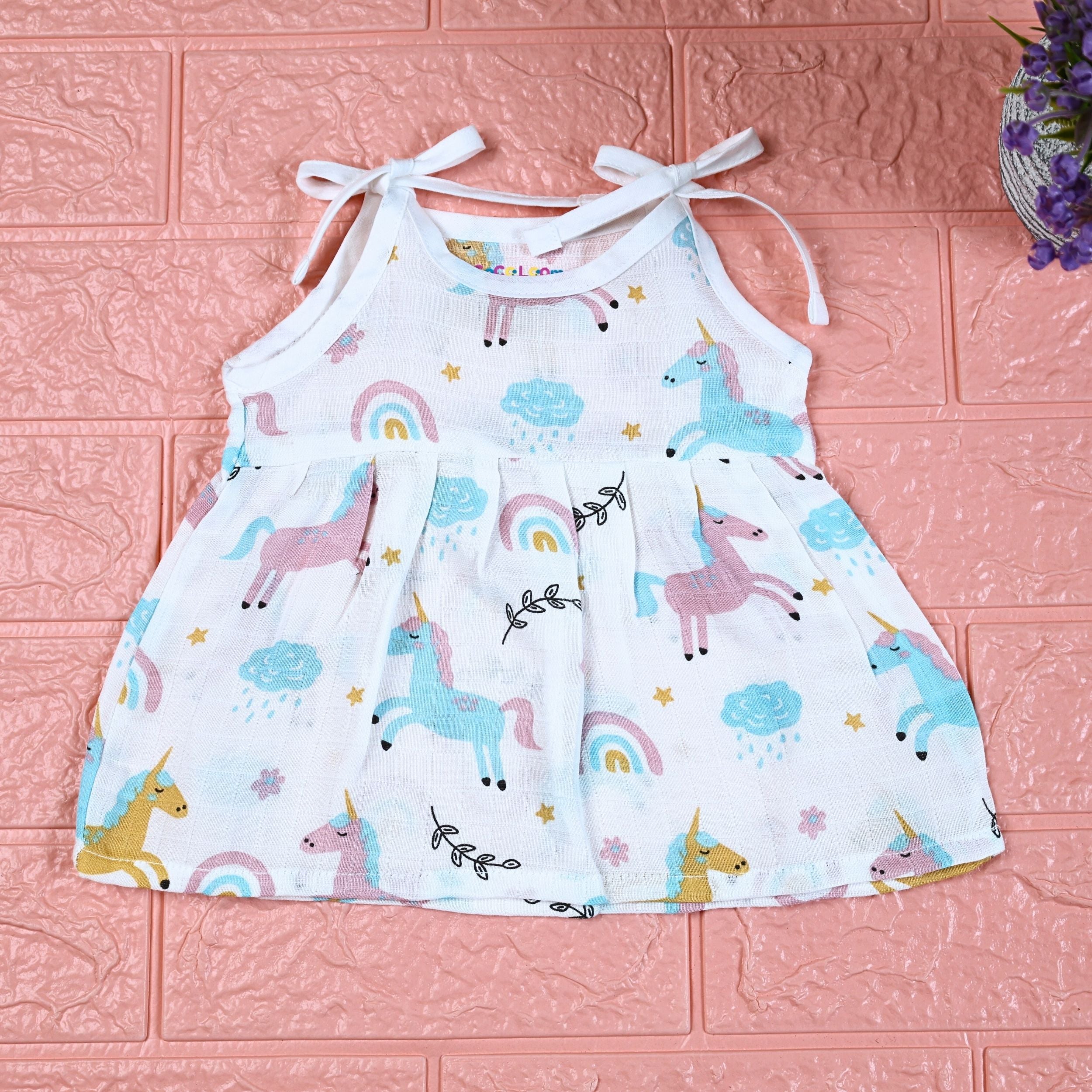 Unicorn baby sleeveless frock in white with tie up shoulders, printed with unicorn and rainbow patterns