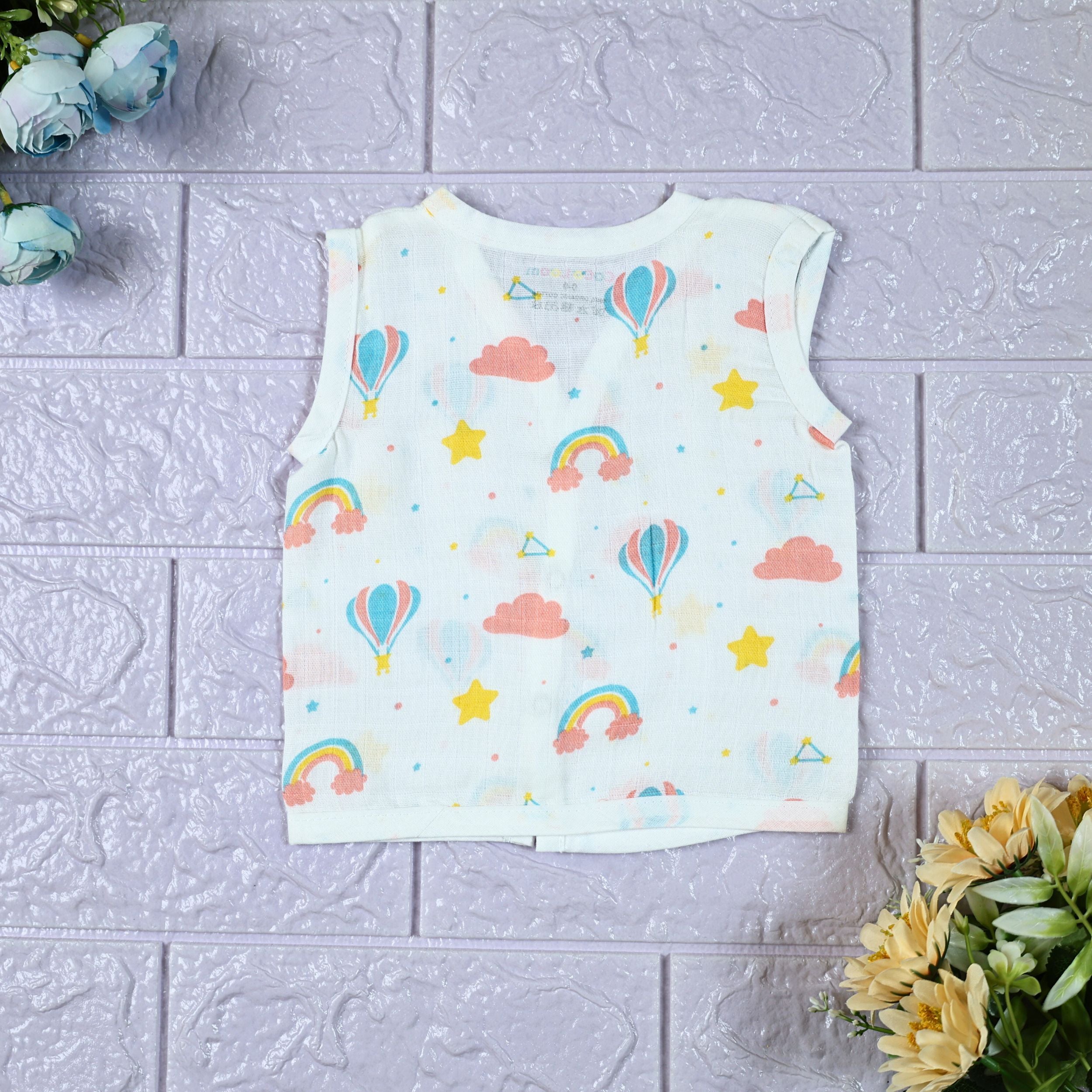 Rainbow Rides baby sleeveless top in white with snap buttons, printed with rainbows, air balloons, clouds, and stars.