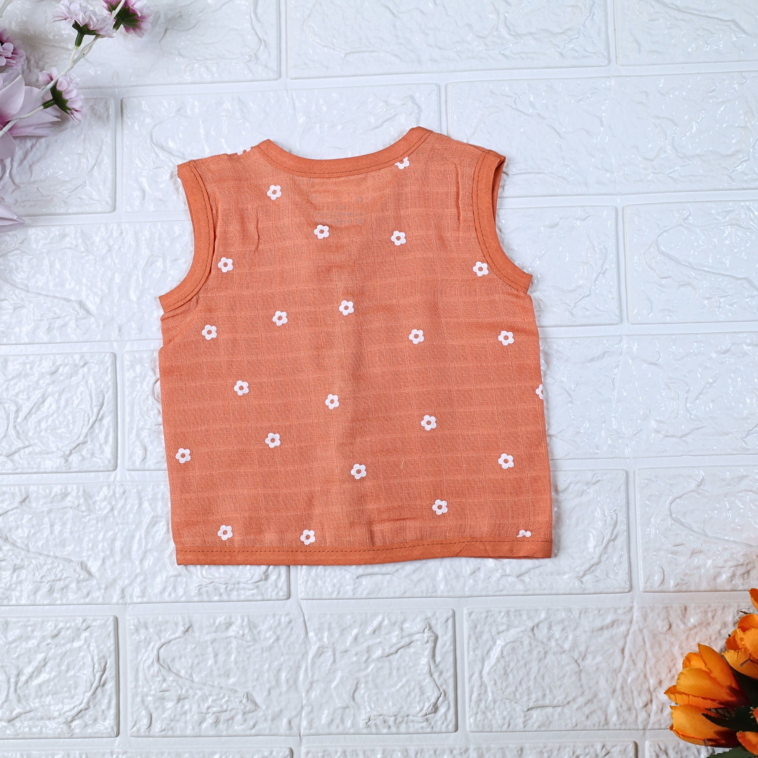 Daisy Daze baby sleeveless top in orange color with snap buttons printed with white floral patterns