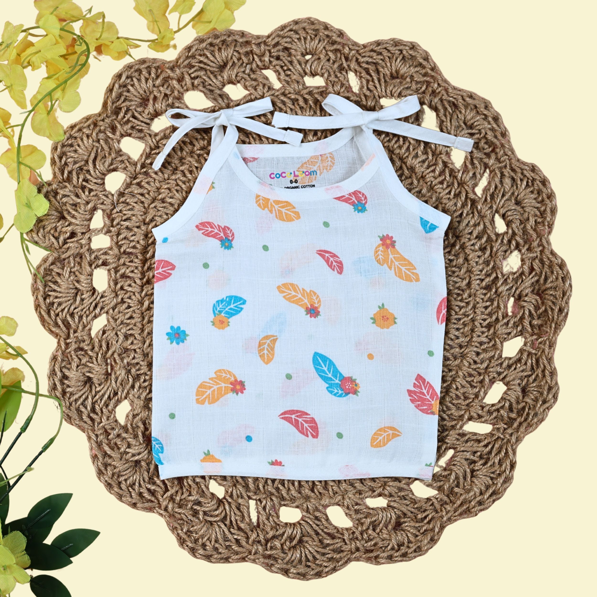 Feathers baby top in white with tie up shoulders, printed with colourful leaf patterns