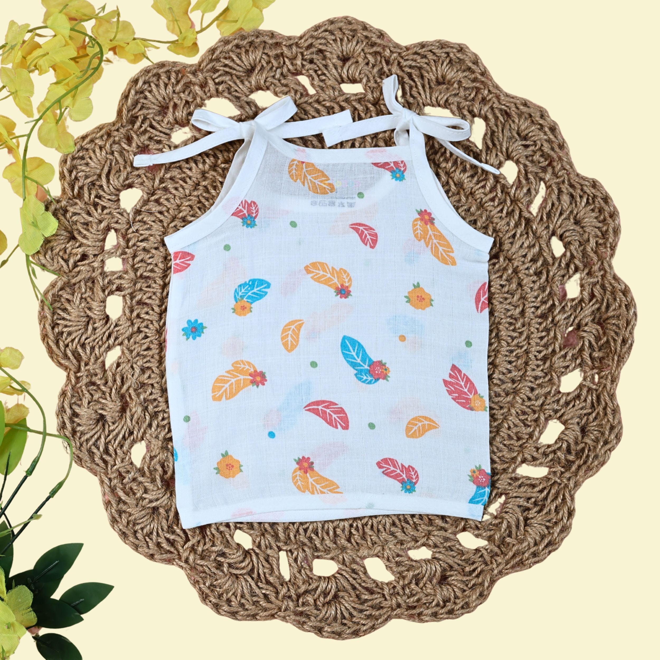 Feathers baby top in white with tie up shoulders, printed with colourful leaf patterns