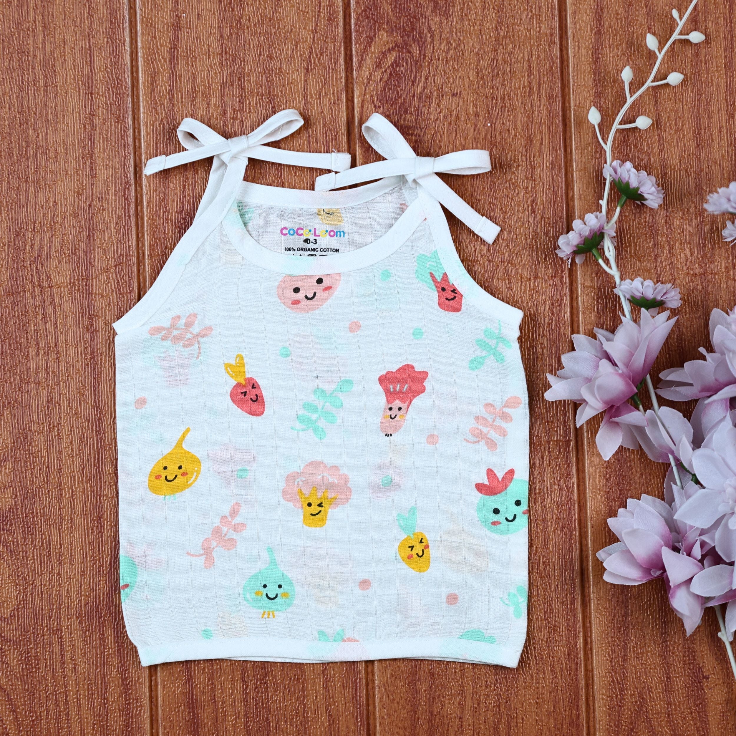 Little Veggies baby sleeveless top in white with tie up shoulders, printed with colorful veggie patterns