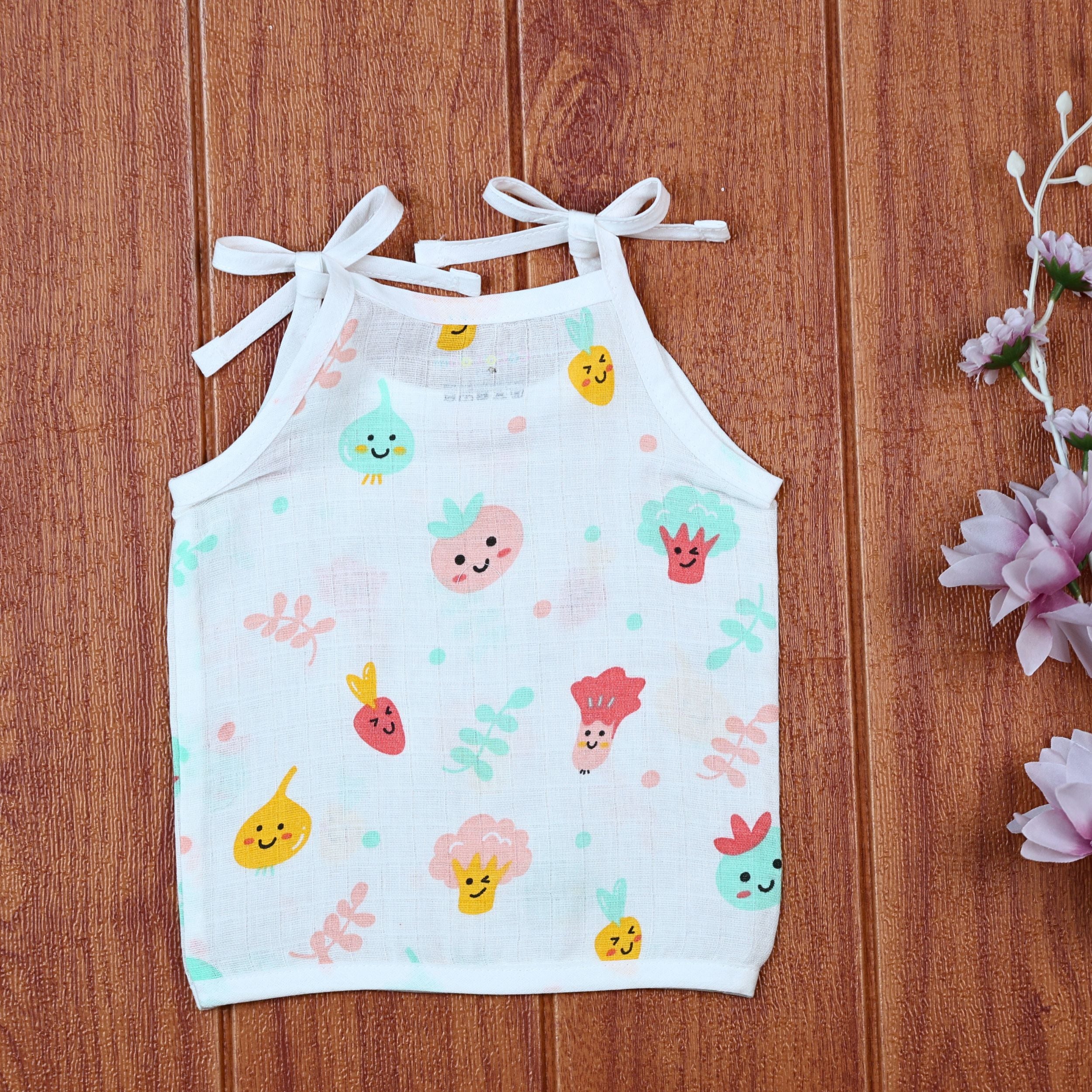 Little Veggies baby sleeveless top in white with tie up shoulders, printed with colorful veggie patterns
