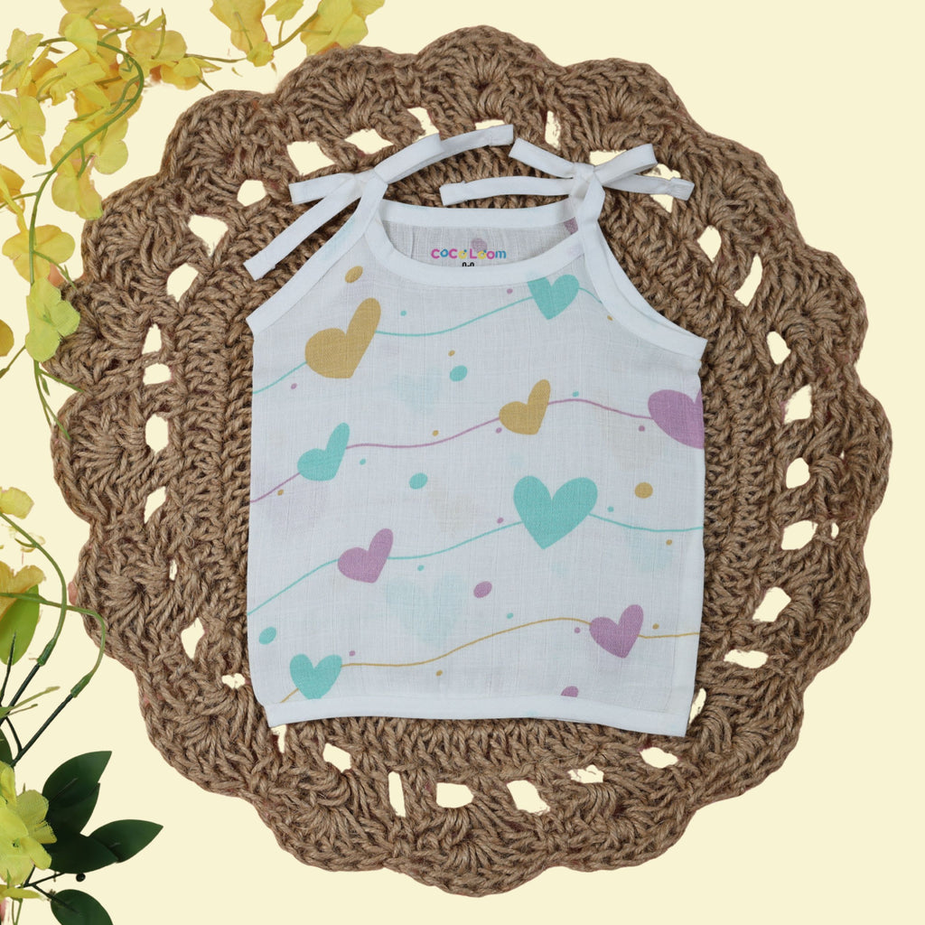 Love Lines baby top in white with tie up shoulders, printed with pastel pink, green and yellow heart patterns