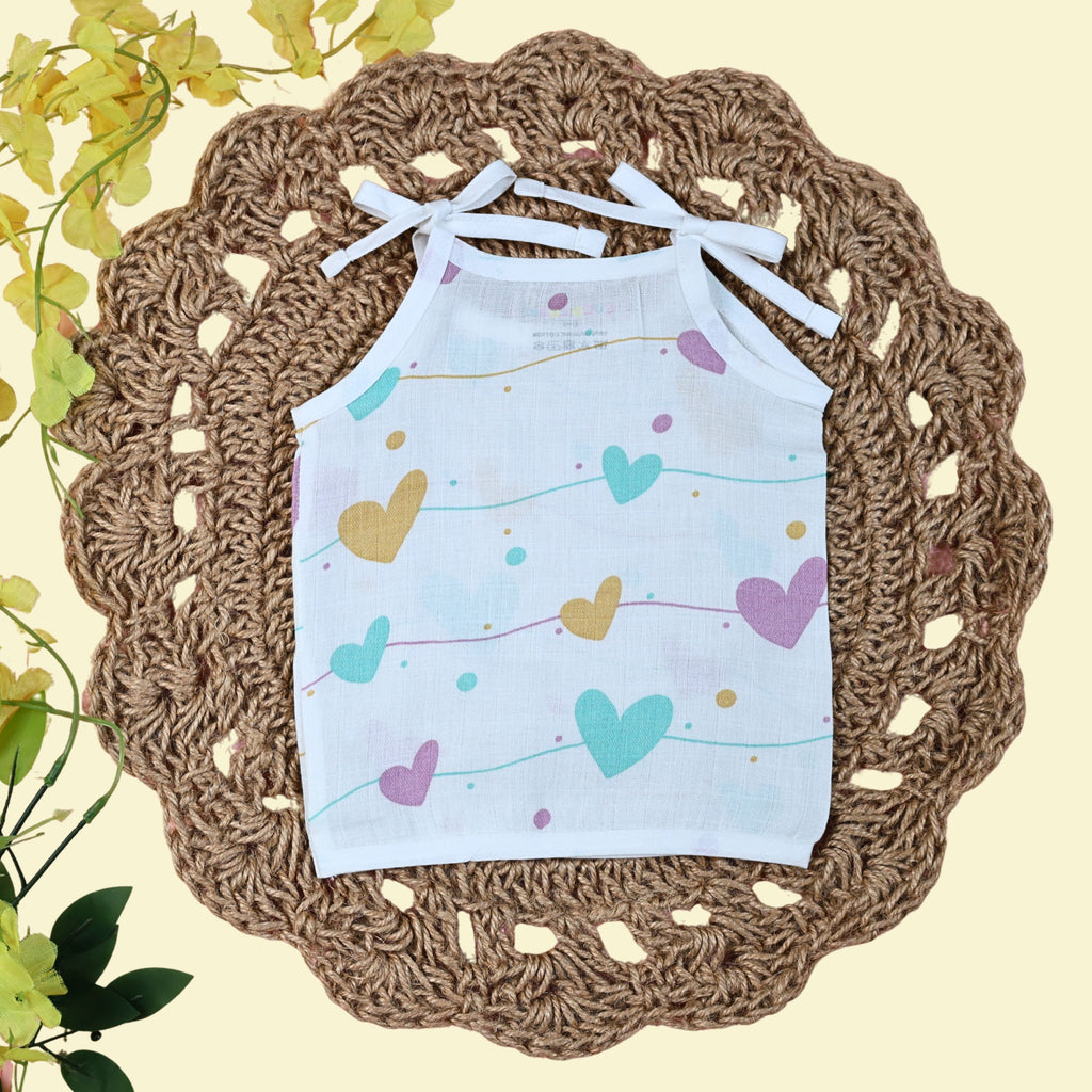 Love Lines baby top in white with tie up shoulders, printed with pastel pink, green and yellow heart patterns