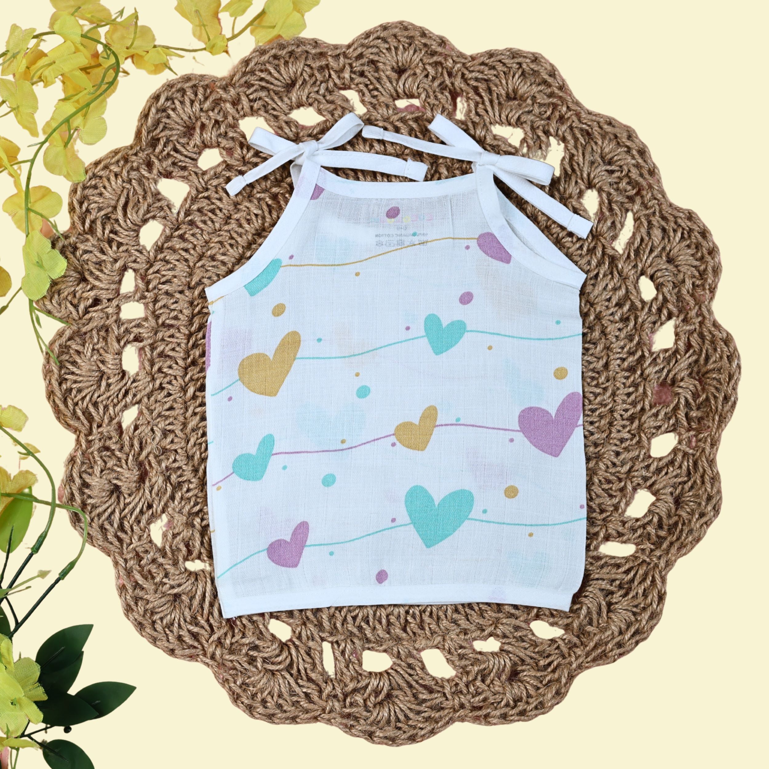 Love Lines baby top in white with tie up shoulders, printed with pastel pink, green and yellow heart patterns