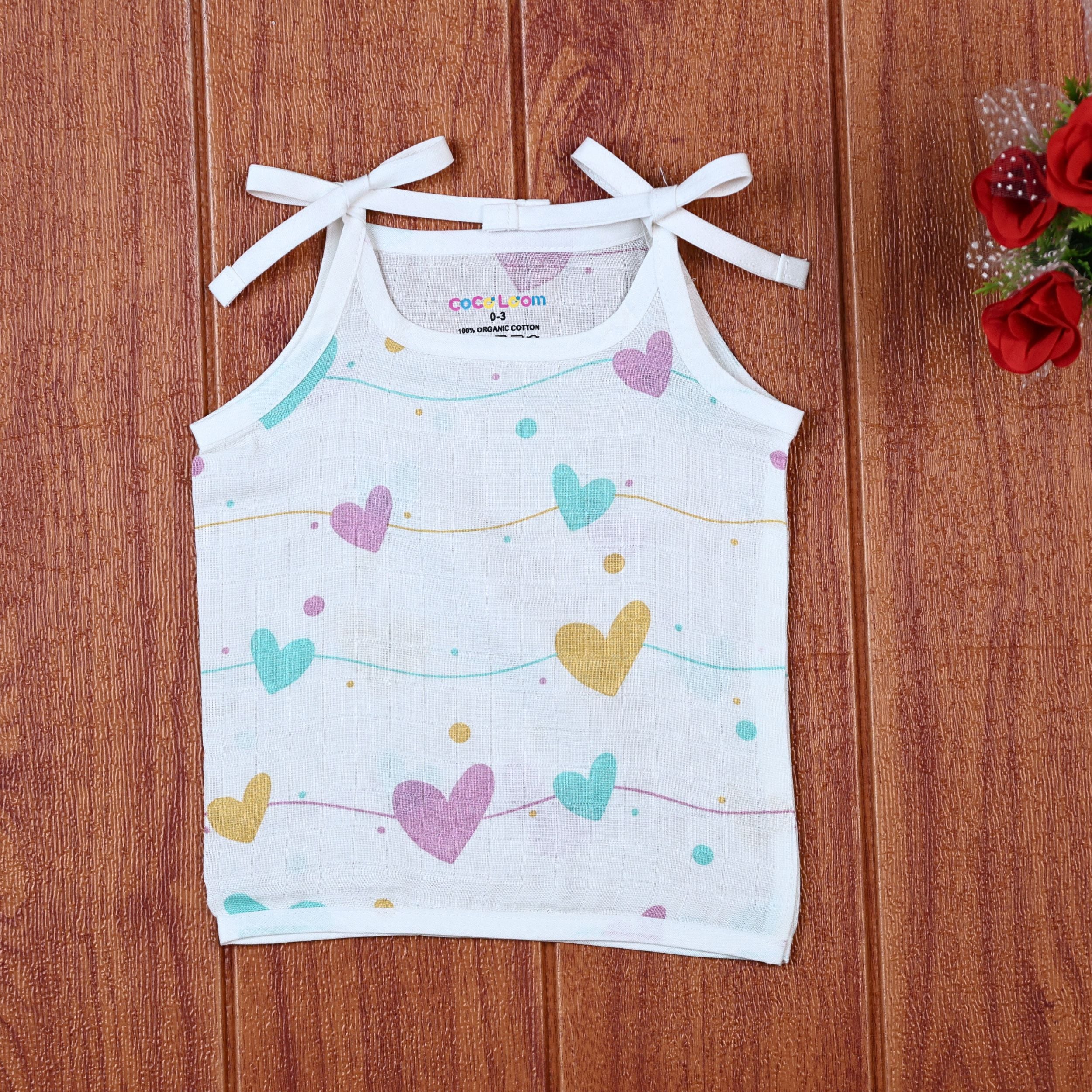 Love Lines baby top in white with tie up shoulders, printed with pastel pink, green and yellow heart patterns