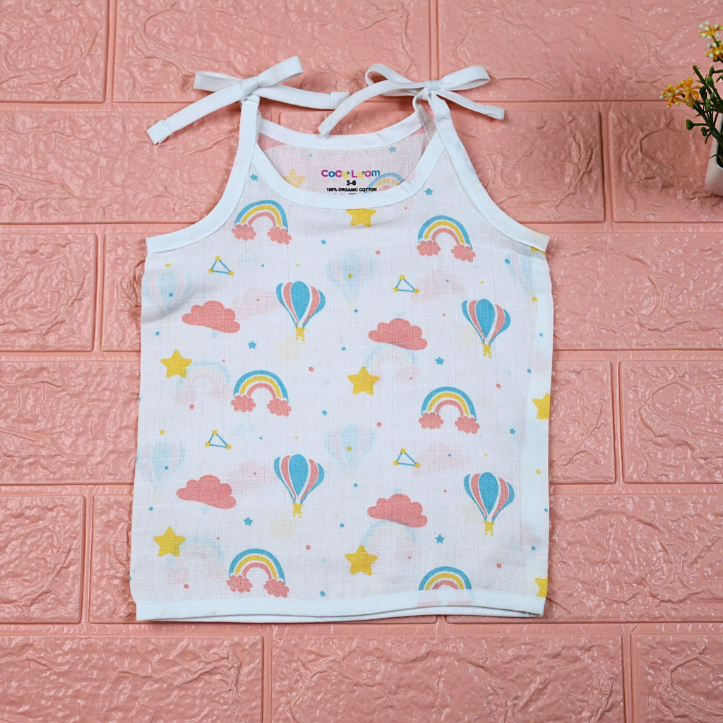Rainbow Rides baby top in white with tie-up shoulders, printed with rainbows, air balloons, clouds, and stars.