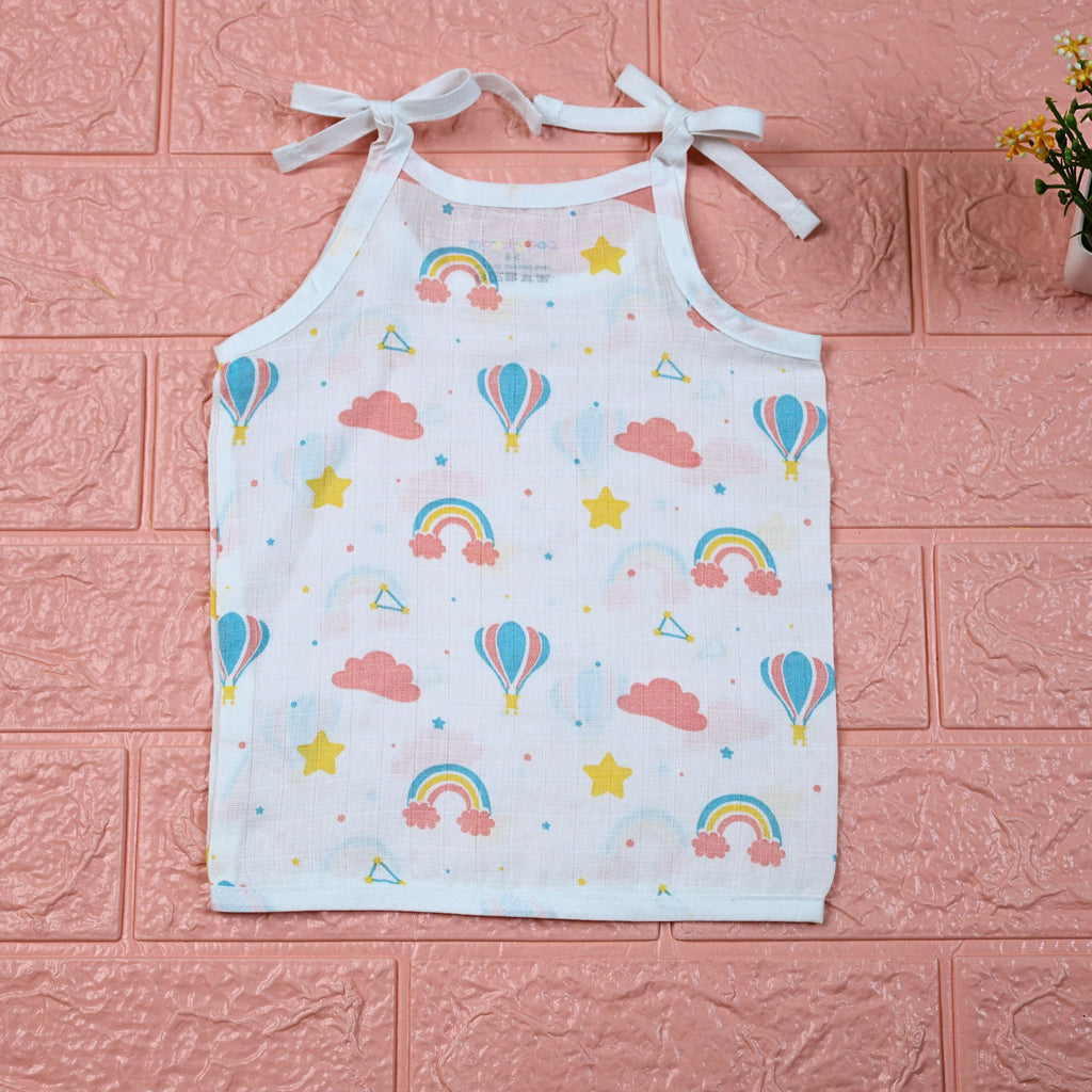 Rainbow Rides baby top in white with tie-up shoulders, printed with rainbows, air balloons, clouds, and stars.