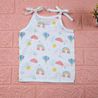 Rainbow Rides baby top in white with tie-up shoulders, printed with rainbows, air balloons, clouds, and stars.