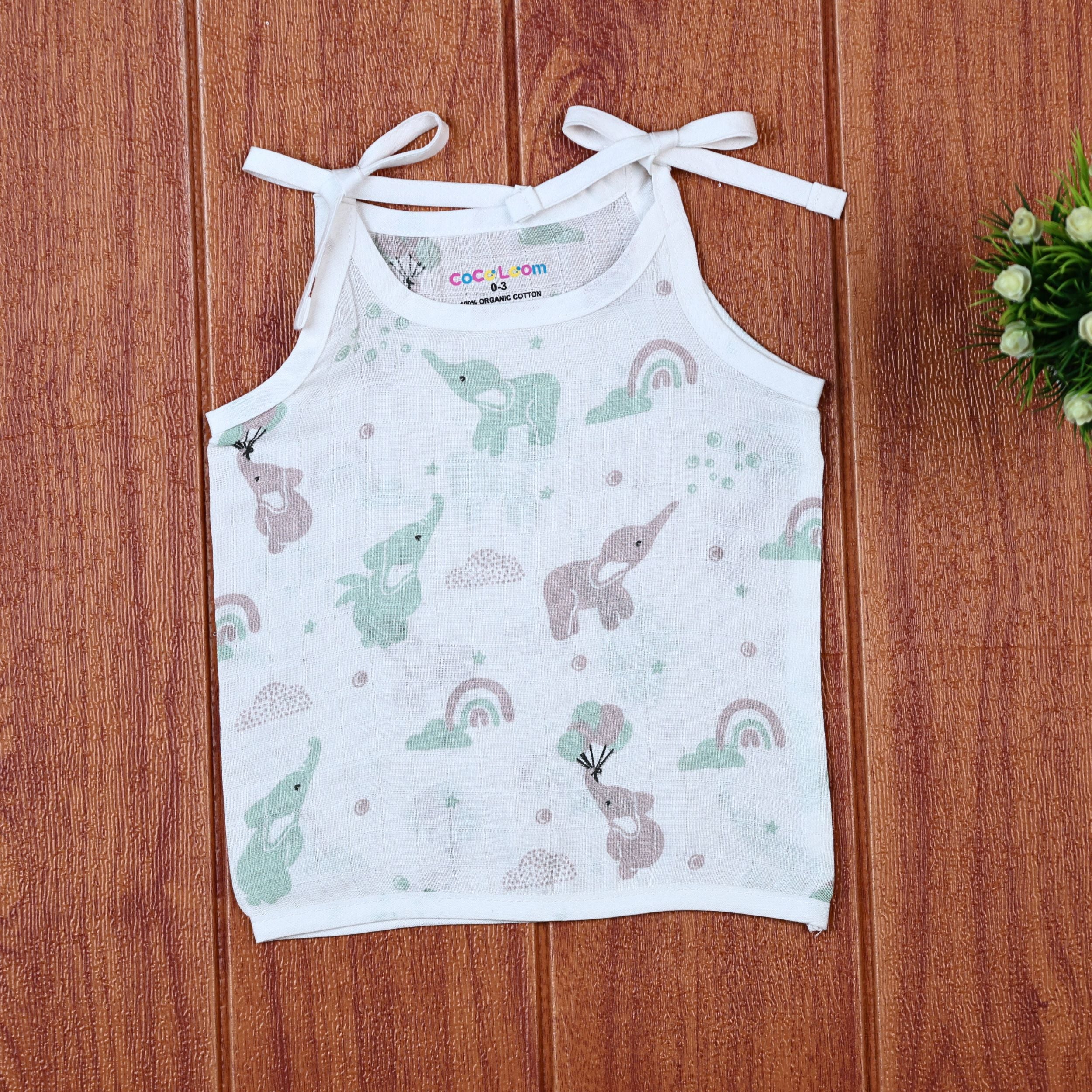 Tiny Tusks baby top in white with shoulder knots, with elephant, clouds and rainbow
 prints in gentle green and brown
 shades.