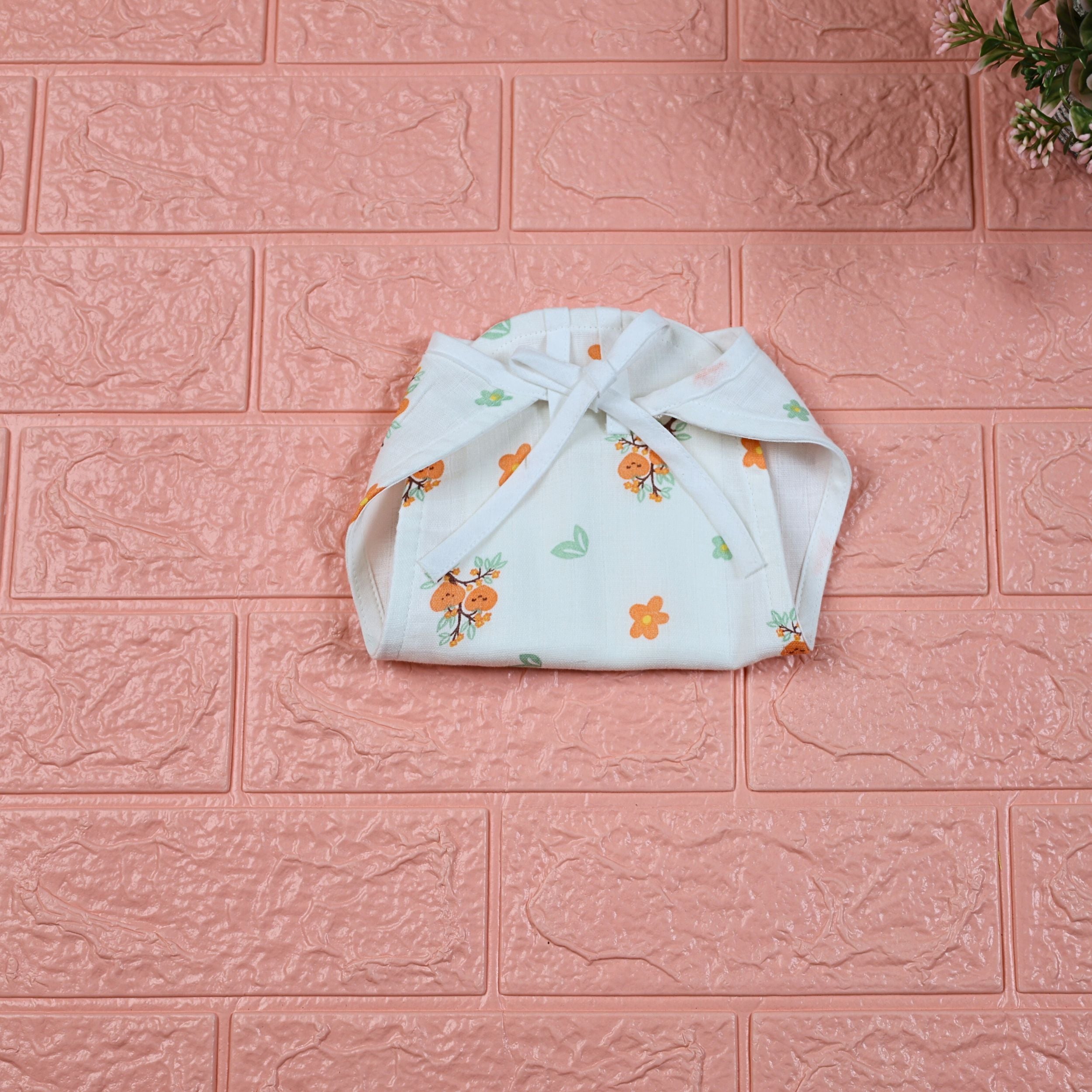 Citrus Bloom Baby nappy in white with tie up knot, printed with orange floral patterns