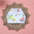 Little Dino Baby Nappy in white with tie up knot, printed with orange and green dinosaur design