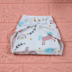 Unicorn Baby nappy in white with tie up knot, printed with unicorn and rainbow patterns