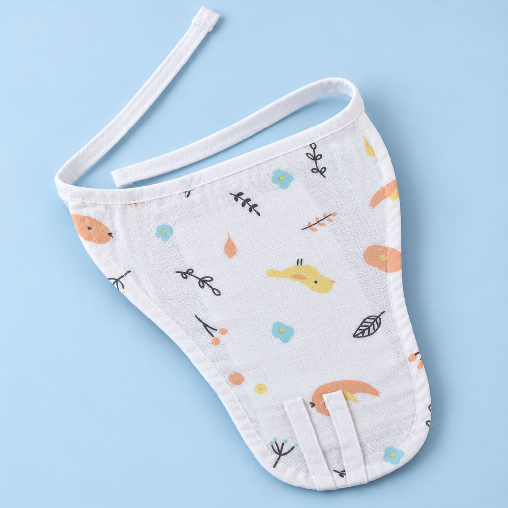 A white muslin baby nappy/langot with a cute, colorful woodland print of birds, leaves, and dots, laid flat on a light blue background.