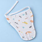 A white muslin baby nappy/langot with a cute, colorful woodland print of birds, leaves, and dots, laid flat on a light blue background.