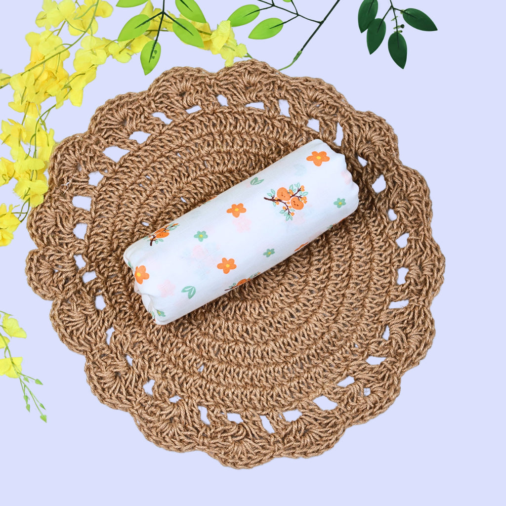 Citrus Bloom Baby Swaddle in white printed with orange floral patterns