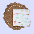 Farm Tales Baby Swaddle in white printed with farm-themed pattern
